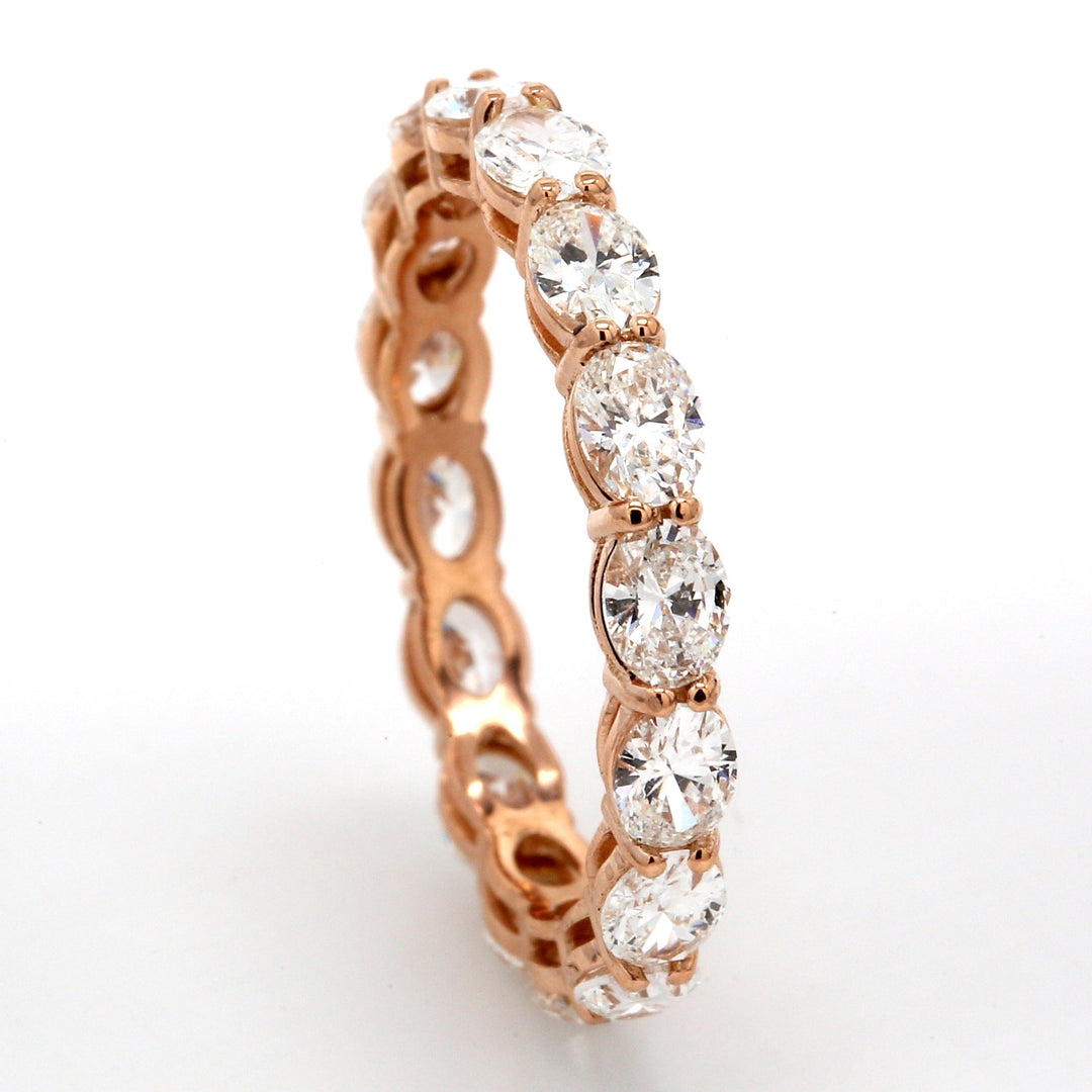 East to west style eternity band in 18K RG with basket prong set (16) oval cut diamonds.  D2.18ct.t.w.  Size 6.5