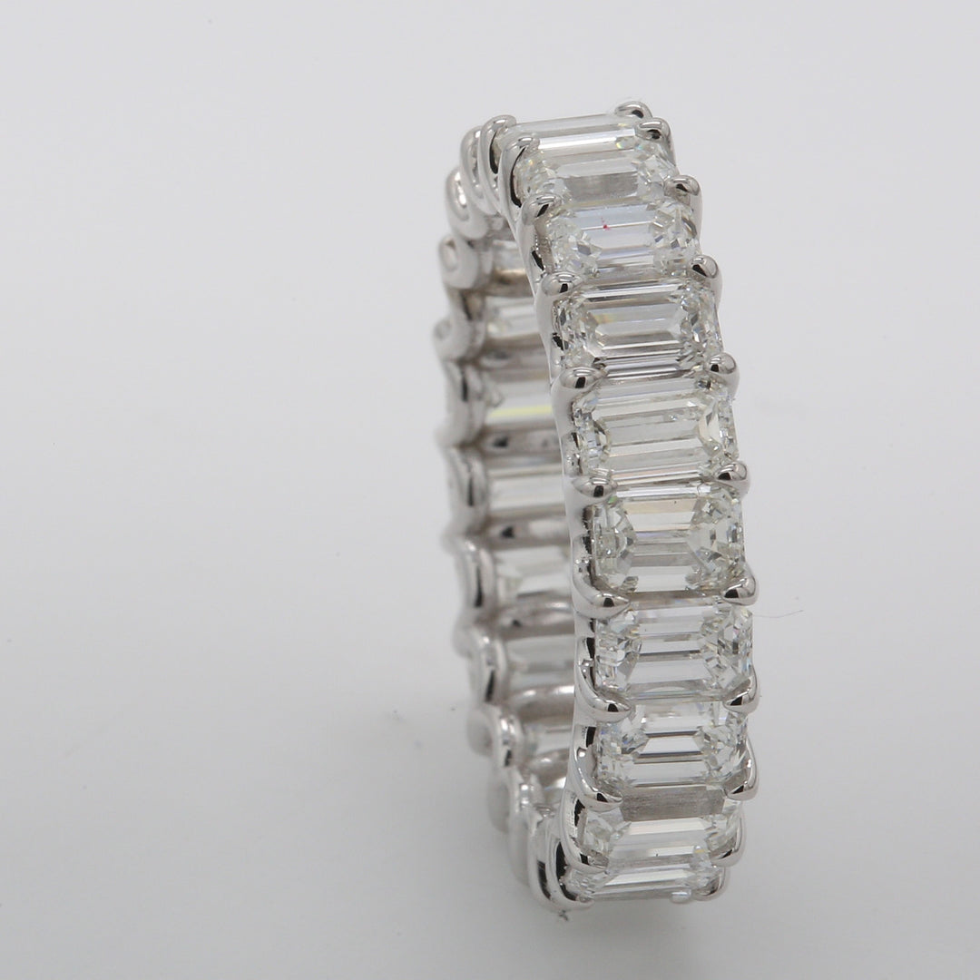 Eternity band in platinum with shared U-prong basket set (22) emerald cut diamonds.  D6.68ct.t.w.  Size 7.25